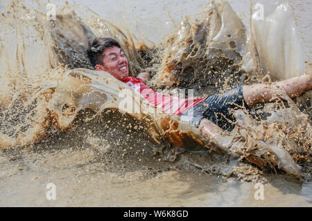 Chinese villagers of the Hakka people carry a golden statue of ancient Chinese general Guan Gong down to waterlogged fields and splash water during a Stock Photo