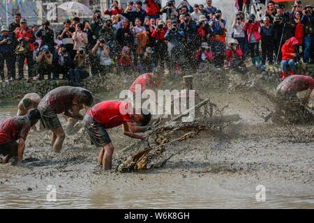 Chinese villagers of the Hakka people carry a golden statue of ancient Chinese general Guan Gong down to waterlogged fields and splash water during a Stock Photo