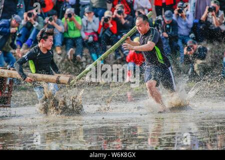 Chinese villagers of the Hakka people carry a golden statue of ancient Chinese general Guan Gong down to waterlogged fields and splash water during a Stock Photo