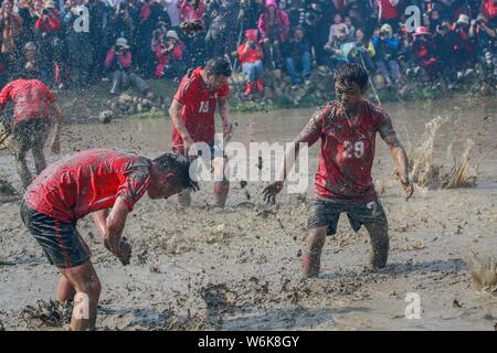 Chinese villagers of the Hakka people carry a golden statue of ancient Chinese general Guan Gong down to waterlogged fields and splash water during a Stock Photo