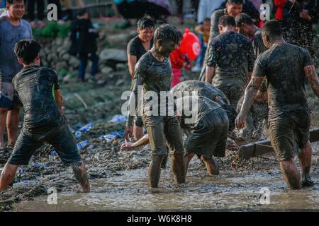 Chinese villagers of the Hakka people carry a golden statue of ancient Chinese general Guan Gong down to waterlogged fields and splash water on the st Stock Photo