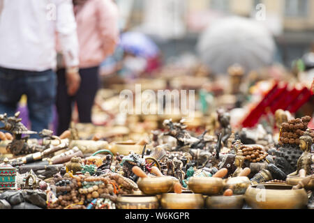 (Selective focus) Close-up view of some souvenirs (singing bowls, hand created statues and Rudraksha necklace) on a street market stall in Kathmandu. Stock Photo