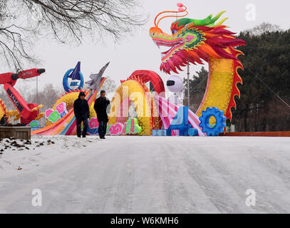 Pedestrians walk past a colorful lantern on display ahead of the 2018 Shenyang International Colorful Lantern Cultural Festival in Shenyang city, nort Stock Photo