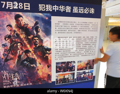 --FILE--A Chinese filmgoer walks past a poster of the Chinese action movie "Wolf Warriors 2" directed by Wu Jing at a cinema in Yichang city, central Stock Photo