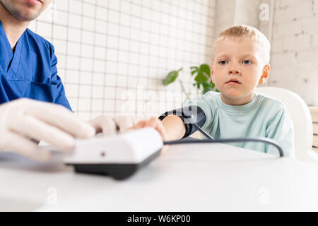 Little boy visiting doctor in hospital. Measuring blood pressure and checking pulse Stock Photo