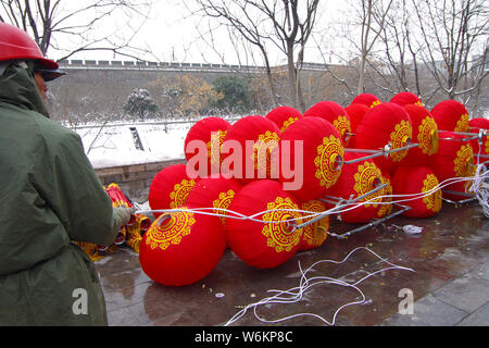 A Chinese worker hangs up red lanterns to celebrate the upcoming Spring Festival or the Chinese New Year (Year of the Dog) on a street in Xi'an city, Stock Photo