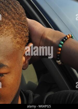 young man taking a picture of his wrist with his colorful bracelet on Stock Photo