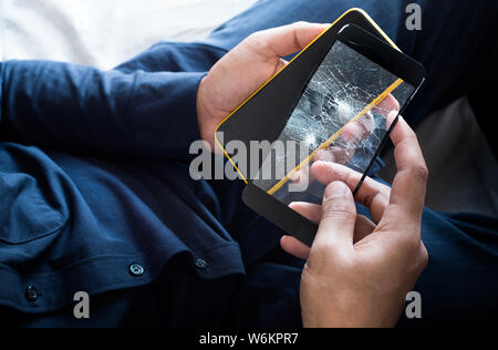 Young male holding smartphone and broken of tempered glass ( film screen).protection and gadget accessory concepts ideas Stock Photo