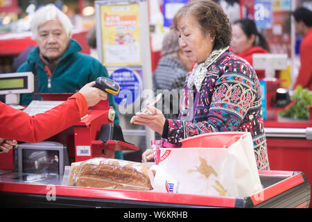 --FILE--A Chinese cashier scans the QR code through mobile payment service Alipay of Alibaba Group on the smartphone of a customer at a supermarket in Stock Photo