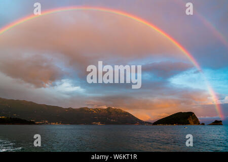 Montenegro, Beautiful colorful huge rainbow over the coast of budva at sunset after rain and heavy thunderstorm Stock Photo