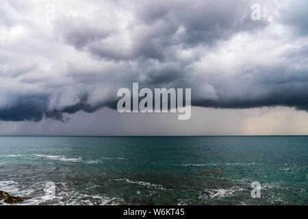 Montenegro, Spectacular storm front of dark dramatic sky with heavy rain coming fast over azure ocean water of budva coast in summer Stock Photo