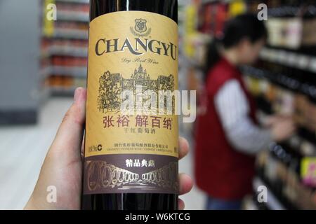 --FILE--A customer shops for a bottle of Changyu dry red wine at a supermarket in Nantong city, east China's Jiangsu province, 10 June 2016.   China's Stock Photo