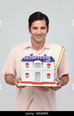 South Indian man holding a model of dream home and smiling Stock Photo ...