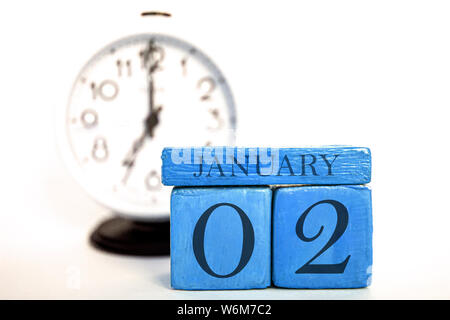 january 2nd. Day 2 of month, handmade wood cube calendar and alarm clock on blue color. winter month, day of the year concept. Stock Photo