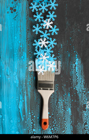 Concept top view flat lay background in blue and white with painting brush loaded with paper snowflakes Stock Photo
