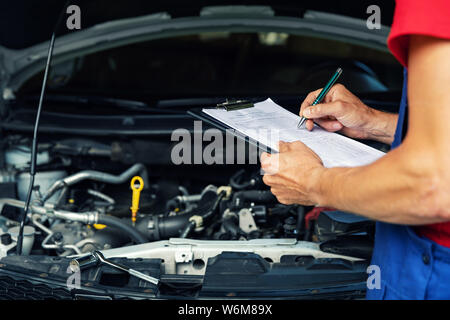 car maintenance and repair - mechanic writing checklist paper on clipboard Stock Photo