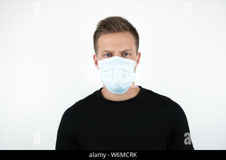handsome young man in black t-shirt wearing medical mask on isolated white background Stock Photo