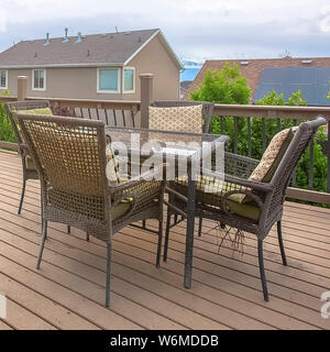 Square frame Wicker glass table and wicker chairs with cushions on the balcony of a home Stock Photo