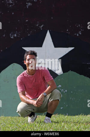 Young man sitting in front of a background with a big star painted on it Stock Photo