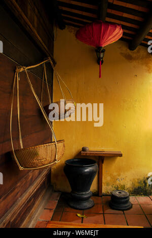 Red chinese lantern, vintage furniture and equipment on the grunge yellow painted wall background in old chinese building Stock Photo