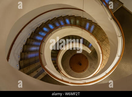 Spiral Staircase Leads Down Several Floors With Dramatic Lighting. Stock Photo