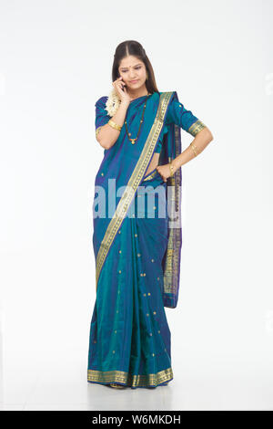South Indian woman talking on mobile phone with her finger in mouth ...