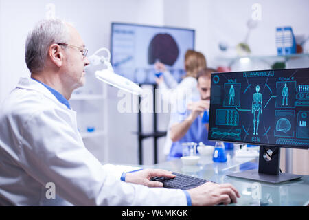 Experienced senior technician working on computer in a laboratory science. Senior engineer typing. Stock Photo