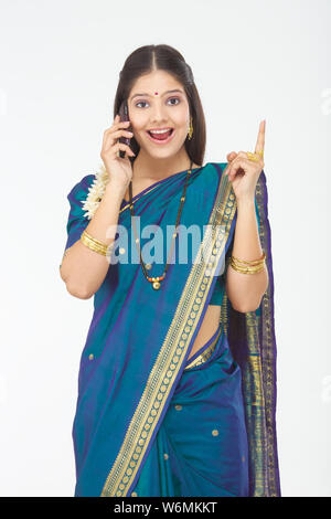 South Indian woman talking on mobile phone and pointing Stock Photo