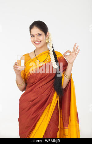 South Indian woman holding glass of water and showing ok sign Stock Photo
