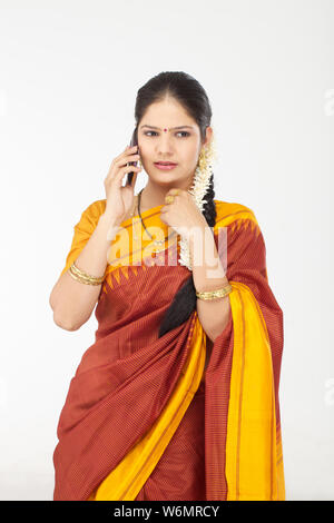 South Indian woman talking on mobile phone with her finger in mouth ...