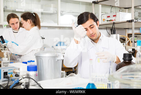 Intelligent student performing experiments in university laboratory, using mechanical lab pipette for mixing chemicals Stock Photo