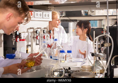 Two female students of Faculty of Chemistry performing experiments in university laboratory, recording results in workbook Stock Photo
