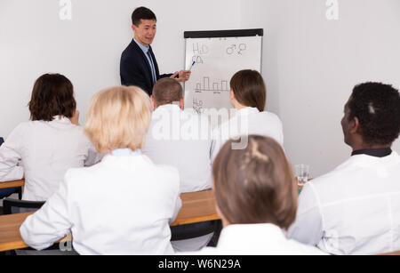 Smiling young male professor giving presentation for medics in convention hall Stock Photo