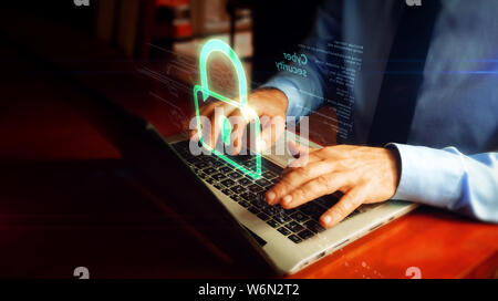 Man typing on laptop with padlock hologram screen over keyboard. Cyber security, computer protection and internet safety concept. Stock Photo