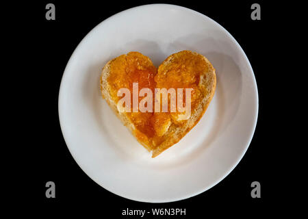 healthy food hearth shaped bread slice with jam marmalade isolated on black Stock Photo