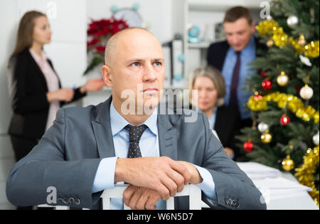 Business team tensely solving problems in office with offended man foreground Stock Photo