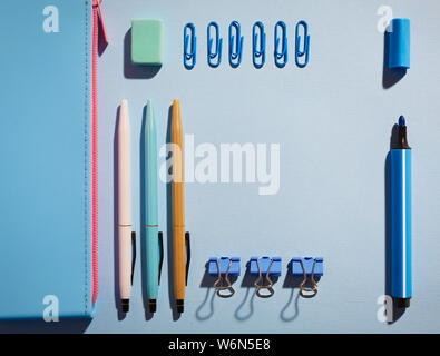 Near blue pencil case lie pens, rubber, markers, and paper clips Stock Photo