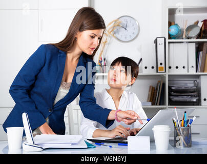 Portrait of two successful businesswomen confidently working on laptop in modern office Stock Photo