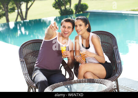 Man sitting at the poolside and showing something to his wife Stock Photo