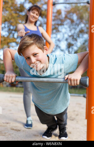 Preteen boy doing push-ups on gymnastics bar during workout with his ...