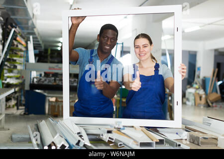 Two masters are working with window frame in the window workshop. Stock Photo