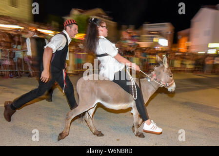 Tribunj, Croatia. 01st Aug, 2019. A woman rides a donkey during