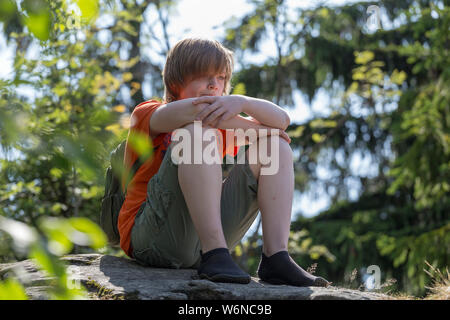 tired boy with minimalist shoes resting on the summit, Großer Riedelstein, Eck, Bavarian Forest, Bavaria, Germany Stock Photo