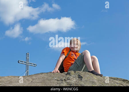 boy with minimalist shoes sitting on the summit of Rauchröhren (smoke tubes), Eck, Bavarian Forest, Bavaria, Germany Stock Photo