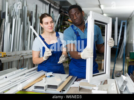 Two masters are working with window frame in the window workshop. Stock Photo