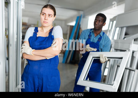 Two masters are conflicting in time working with window frame in the window workshop. Stock Photo