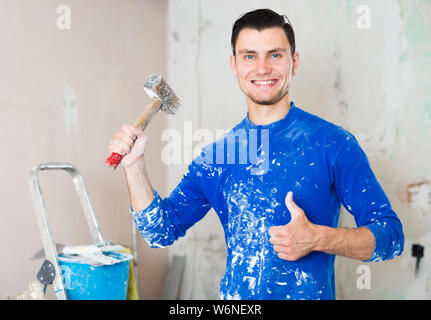 Young happy builder handyman with hammer in hand giving thumbs up Stock Photo