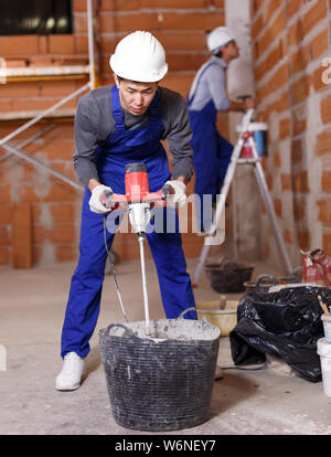 Portrait of two builders in process of finishing work in cottage Stock Photo