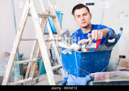 builder handyman choosing necessary tool in toolbox Stock Photo
