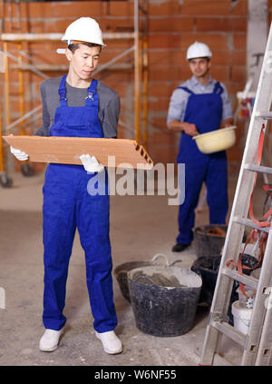 Portrait of two confident workers in uniform inside brick cottage Stock Photo